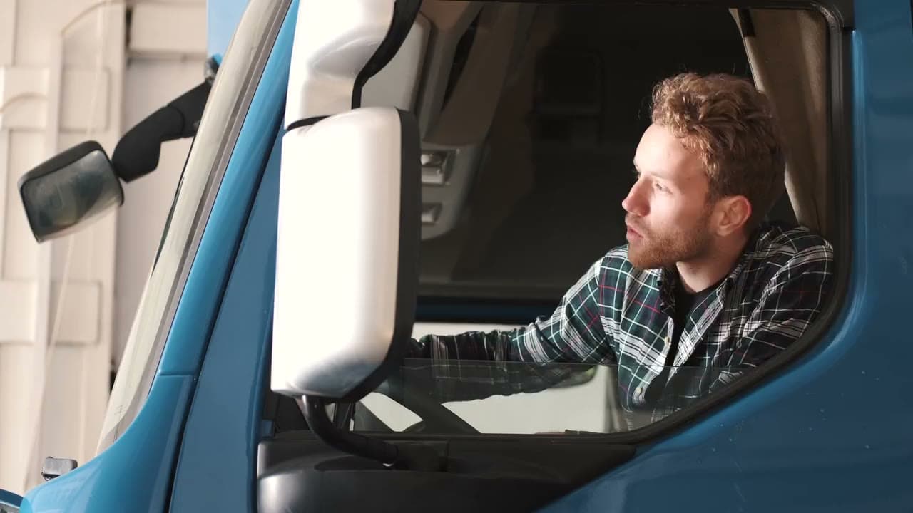 A truck driver looking out the cab window of his truck